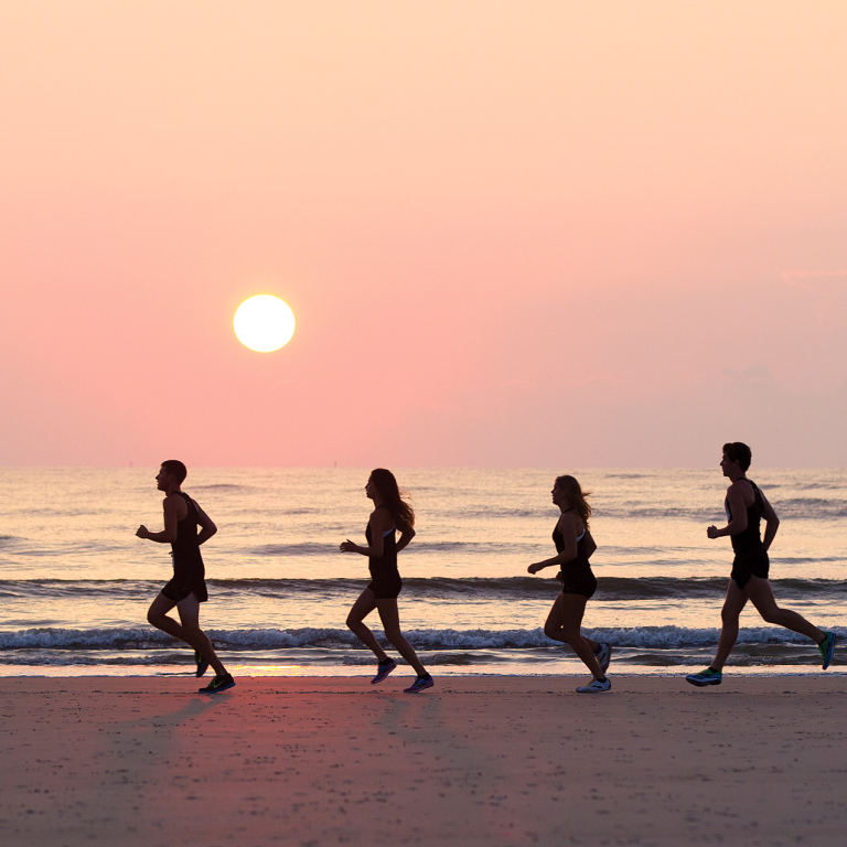 SCAD越野运动员在日落时跑过海滩